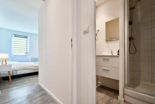 ein Bad mit einer Dusche und ein Schlafzimmer mit einem Bett in der Unterkunft Le Duo - Les Demeures d'Adrien in Carvin