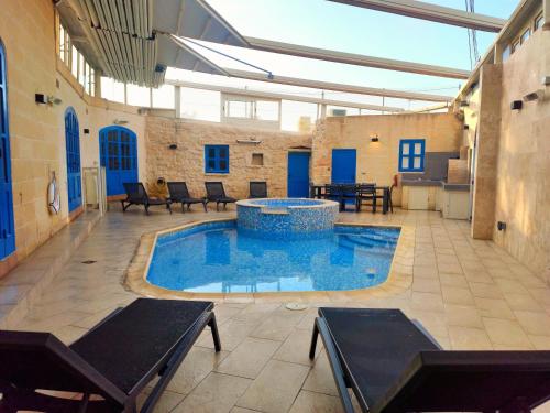 - une piscine dans un bâtiment avec des chaises et une table dans l'établissement Margerita Farmhouse, à Qrendi