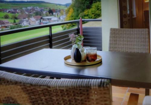 ein Tisch mit einem Teller und einer Vase mit Blumen auf einem Balkon in der Unterkunft Brandenkopfblick in Oberharmersbach