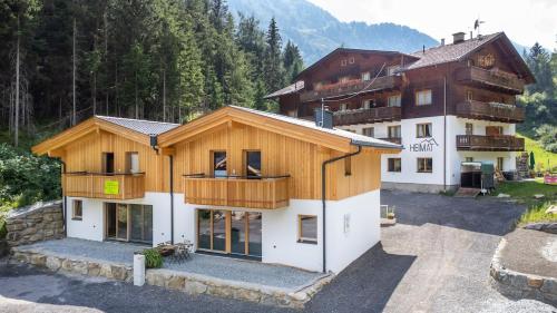 a house with a wooden roof and a building at Ferienhaus Blauer Vogel - kostenfreie Saunanutzung in Prägraten