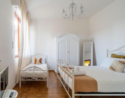 biała sypialnia z łóżkiem i krzesłem w obiekcie La Terrazza sul Ricetto Appartamento Guest w mieście Candelo