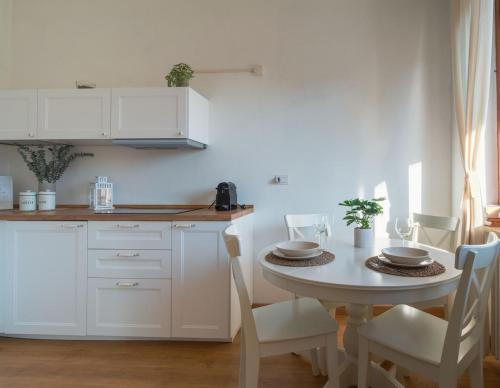 biała kuchnia ze stołem i krzesłami w obiekcie La Terrazza sul Ricetto Appartamento Guest w mieście Candelo