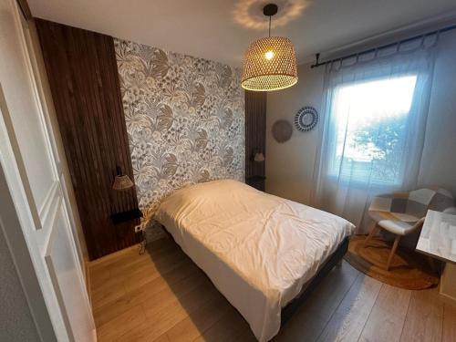 una camera con letto, finestra e lampadario a braccio di Le Calarius - place parking gratuit a Chauray