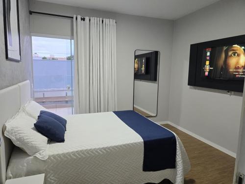 une chambre avec un lit et une télévision à écran plat dans l'établissement Quarto Em Sobrado - Banheiro INDIVIDUAL, Garagem Coberta e TV com streamings, à Campo Mourão