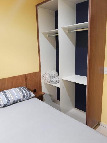 a bedroom with a bed and a closet with shelves at Seu lar em Cascavel in Cascavel