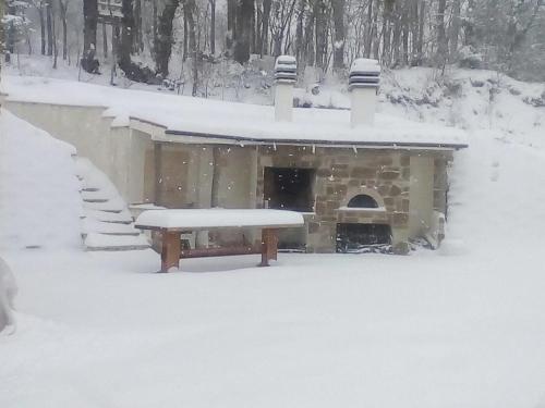Un edificio cubierto de nieve con una chimenea y una mesa de picnic. en Casa Baldoni, en Matelica