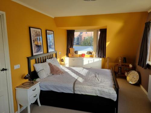 a bedroom with a bed with yellow walls and a window at De Oude Bakkerij in Onderdendam