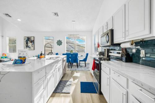 a kitchen with white cabinets and blue accents at Beautiful 5BR 4 baths Themed home near Disney and Universal, Private Pool, Gameroom, baby Crib and more in Kissimmee