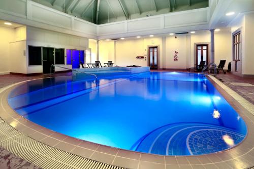 a large pool with blue water in a building at Macdonald Botley Park Hotel & Spa in Southampton