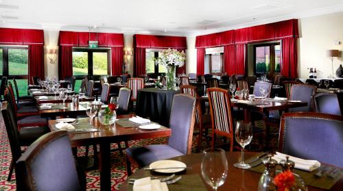 a restaurant with tables and chairs and red curtains at Macdonald Botley Park Hotel & Spa in Southampton