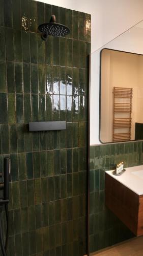 a green tiled bathroom with a sink and a mirror at Palmarea House in Nebbiuno
