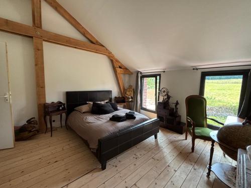 Un dormitorio con una cama en una habitación con ventanas. en Hameau Fleuri, en Pierrefitte-en-Auge