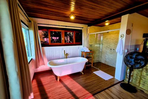 ein großes Badezimmer mit Badewanne und Dusche in der Unterkunft VELINN Pousada Pedras e Sonhos in Monte Verde