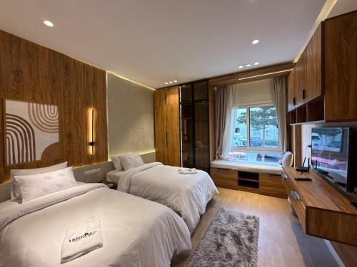 a hotel room with two beds and a flat screen tv at 2BR at The Boulevard Nest Pool - Gym - Café Vibes in New cairo