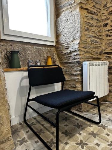 a black chair in a room with a stone wall at A Casiña da Ponte in Lugo