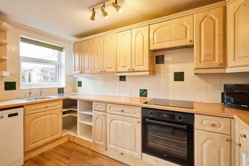 a kitchen with wooden cabinets and a window at Host & Stay - Riders Rest in Wootton