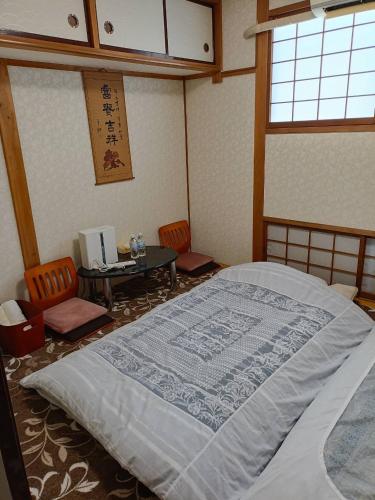 a bedroom with a bed and a table and chairs at 菊の宿 民泊 in Iidamachi