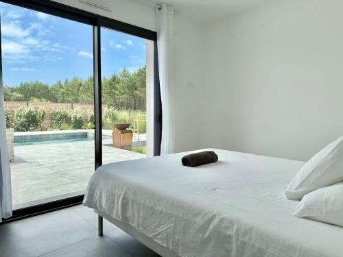 a bedroom with a bed and a large glass window at Villa Amara Piscine 7 personnes in Mios