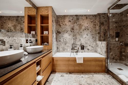 ein Badezimmer mit zwei Waschbecken, einer Badewanne und einer Dusche in der Unterkunft Hotel Annapurna in Courchevel