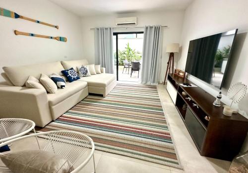 a living room with a couch and a tv at Casa Nova em Maresias in São Sebastião