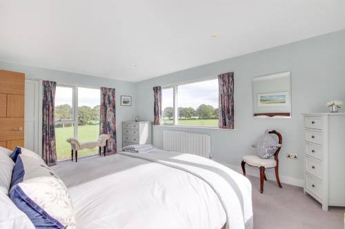a white bedroom with a large bed and windows at Large Heated Pool with Countryside Views in Cowfold