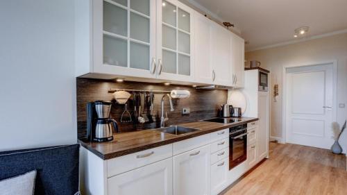 una cucina con mobili bianchi e un lavandino di Strandresidenz Vogelflug Meerblick Fehmarnsund a Fehmarnsund