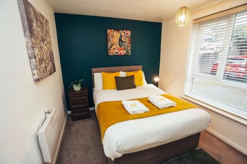 une chambre avec un grand lit avec des oreillers jaunes dans l'établissement Cosy 1-Bed Apartments in Mickleover with Free Parking & WiFi, à Derby