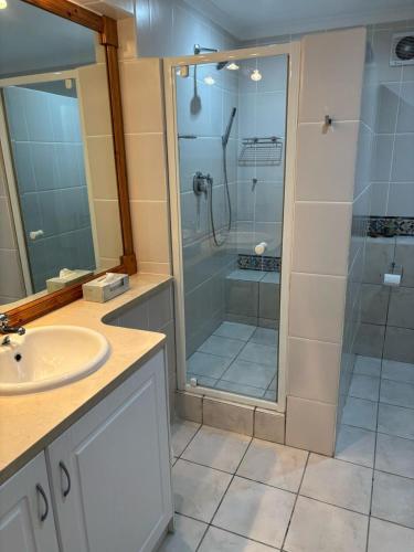 a bathroom with a glass shower and a sink at Whale and Waddle in Rocklands