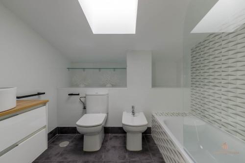 Un baño blanco con inodoro y bañera. en Living4Malaga Sky Garden Duplex, en Málaga