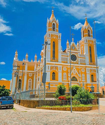 an orange and white church with a blue truck in front at Apartamento completo Excelente localização Centro in Canindé