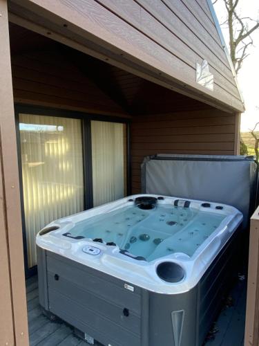 a hot tub sitting on a deck next to a building at Belraugh Mountain View Hot Tub Lodges in Garvagh
