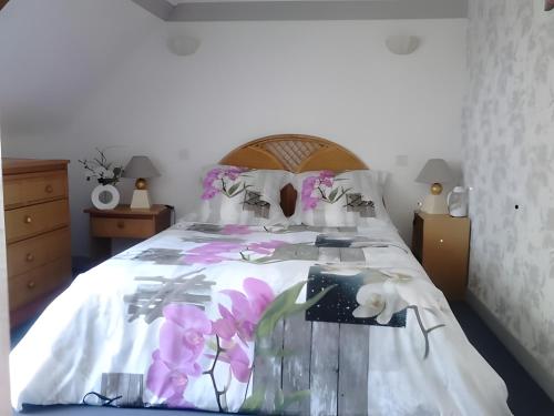 a bedroom with a bed with pink flowers on it at Chambres D'hôtes d'Evelyne in Sainte Anne d'Auray 