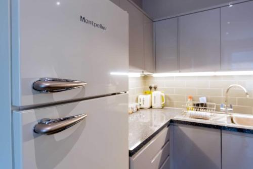 a white kitchen with a refrigerator and a sink at Sandy Bay - Mins To Margate Main Sands in Margate