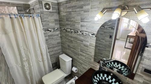 a bathroom with a toilet and a sink and a mirror at Hermoso Departamento Completo en PB in Río Grande