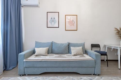 ein blaues Sofa im Wohnzimmer mit blauen Vorhängen in der Unterkunft Апартаменты в ЖК Ирина рядом с Баянтау in Pawlodar