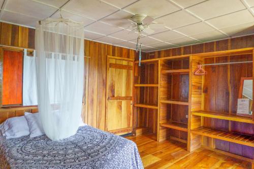 a bedroom with wooden walls and a bed with a curtain at Jodokus Inn in Montezuma