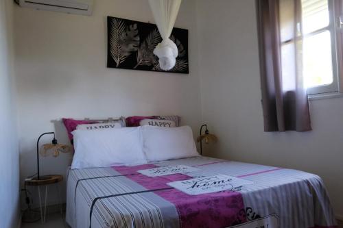 a bedroom with a bed with a purple and white blanket at Lantana in Sainte-Anne
