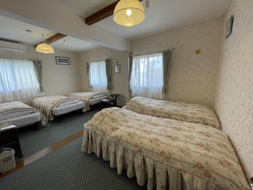 a hotel room with three beds in a room at ペンションあけまの森 in Daisen