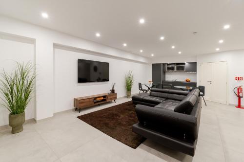 a living room with a black couch and a tv at Bom Sucesso Executive Suites by HostWise in Porto