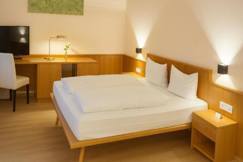 a bedroom with a bed and a desk and a television at Hotel Rheinland in Bad Orb