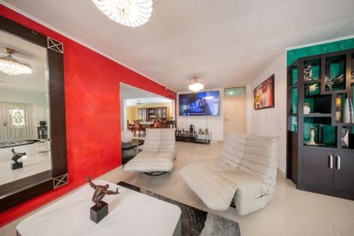 een woonkamer met witte banken en een rode muur bij Villa Laura, Central Spacious Oasis with Private Pool in Willemstad