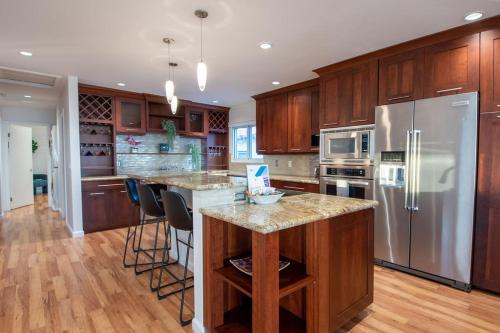 une cuisine avec des armoires en bois et un réfrigérateur en acier inoxydable dans l'établissement Hilltop Hacienda – Private Villa Panoramic Views, à San Diego
