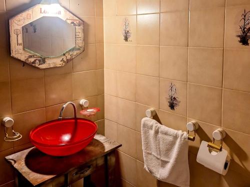 Un baño con un lavabo rojo y un espejo. en Chalet con puerta al arroyo, en Villa General Belgrano