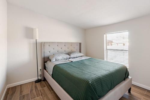 a bedroom with a bed with a green comforter and a window at Entire Home, 7 Minutes from Phoenix Airport in Phoenix