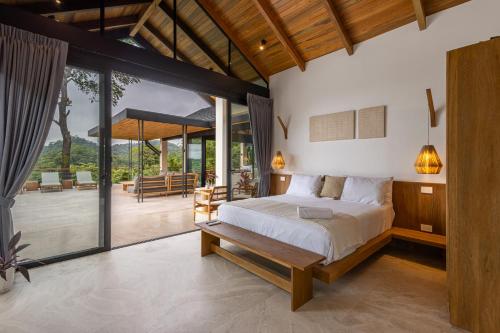 a bedroom with a large bed and a patio at Villa Bahia Oceanview Designer Retreat Malpais in Mal País