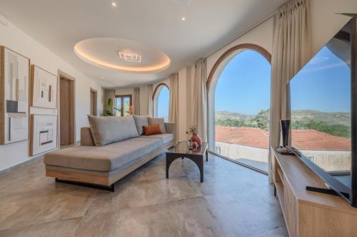 a living room with a couch and a tv at Casa Karinea - Serene Stone House Retreat in Áyios Vasílios