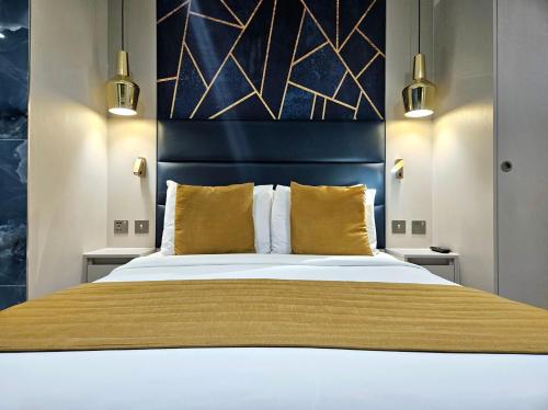 a bedroom with a large bed with yellow pillows at NOX Earls Court in London