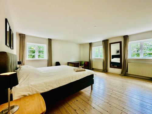 ein Schlafzimmer mit einem Bett und einem Tisch und Fenstern in der Unterkunft Large Holiday Home With Pool On South Lolland Coast in Dannemare