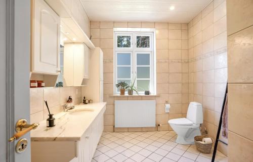 ein Badezimmer mit Toilette und Waschbecken und einem Fenster in der Unterkunft Large Holiday Home With Pool On South Lolland Coast in Dannemare