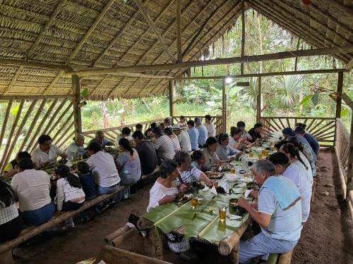 un gruppo di persone sedute a lunghi tavoli in una tenda di Lisan Wasi a Indillana